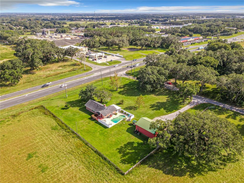 An aerial view shows a house with a pool and a red barn on a lot — 10038 N US HIGHWAY 301, OXFORD, FL