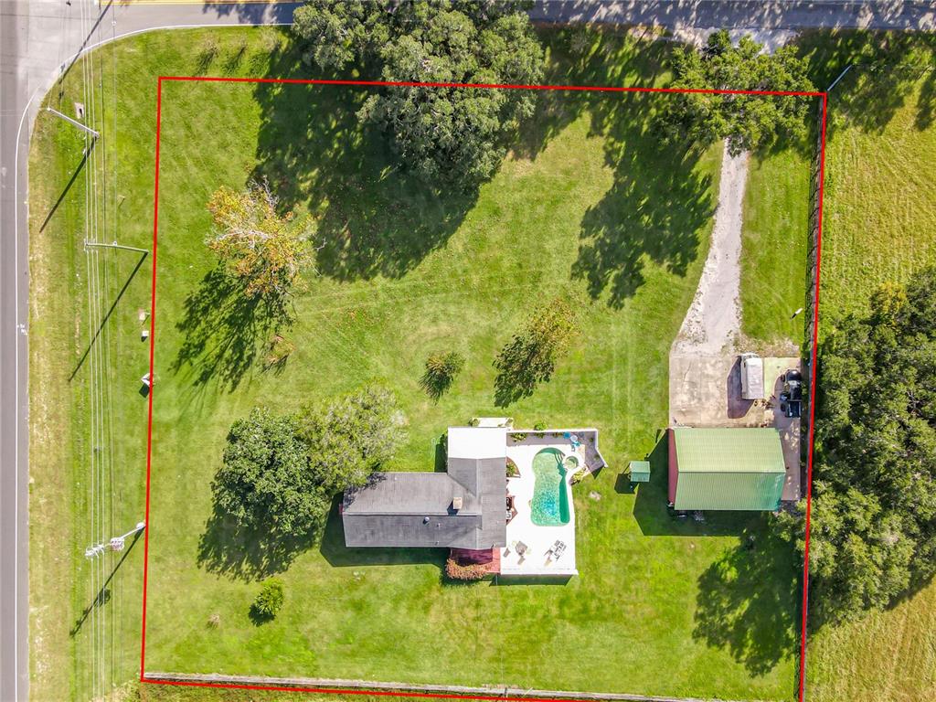 An aerial view shows a house with a pool and a detached garage on a lot — 10038 N US HIGHWAY 301, OXFORD, FL