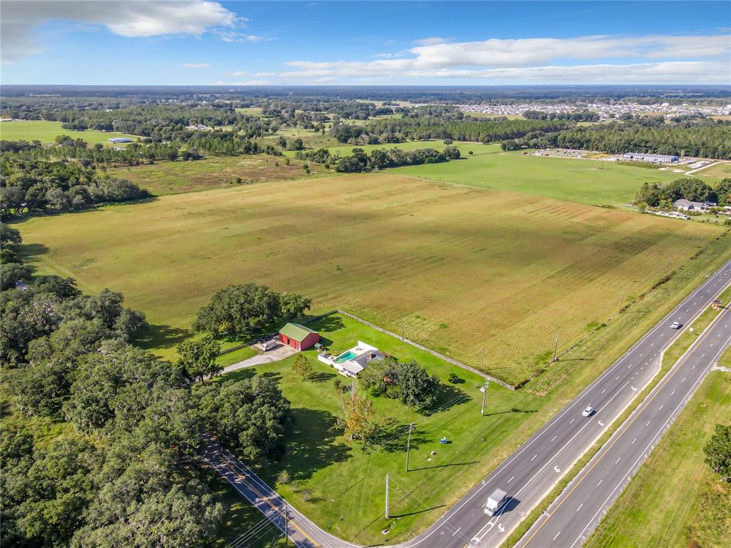 An aerial view shows a house with a pool and barn on a large grassy lot — 10038 N US HIGHWAY 301, OXFORD, FL