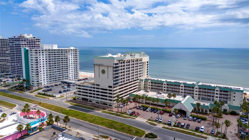 An aerial view shows a large beachfront hotel complex with a parking lot and ocean — 2700 N ATLANTIC AVENUE UNIT 821, DAYTONA BEACH, FL
