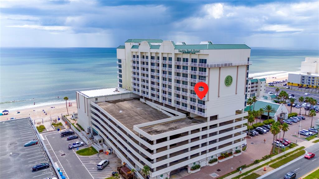 An aerial view shows a large beachfront resort hotel with an attached multi-level parking garage — 2700 N ATLANTIC AVENUE UNIT 821, DAYTONA BEACH, FL