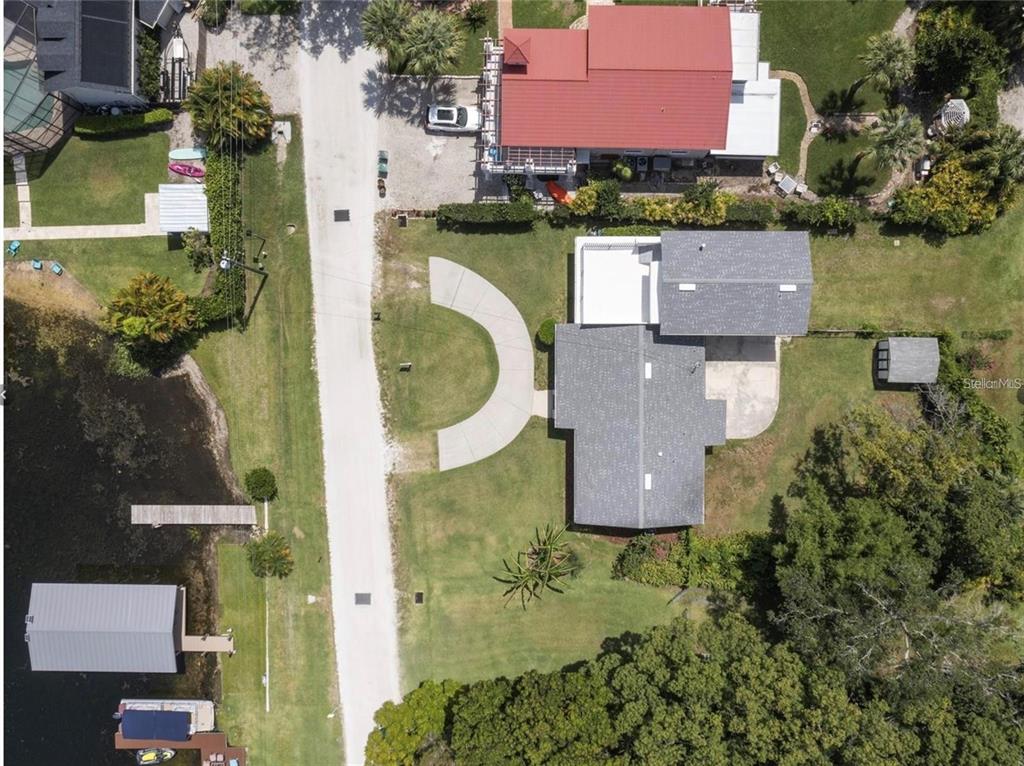 An aerial view shows a house with a gray roof, a circular driveway, and waterfront access — 212 W 1ST AVENUE, WINDERMERE, FL