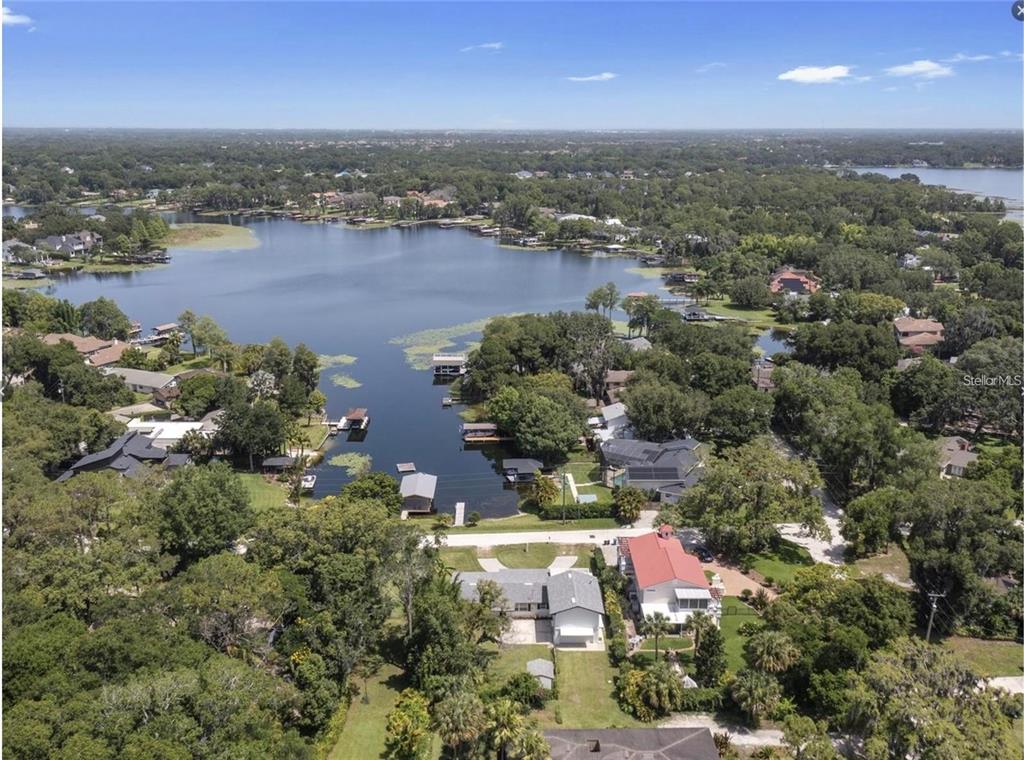 An aerial view shows a waterfront house with a red roof situated near a lake — 212 W 1ST AVENUE, WINDERMERE, FL