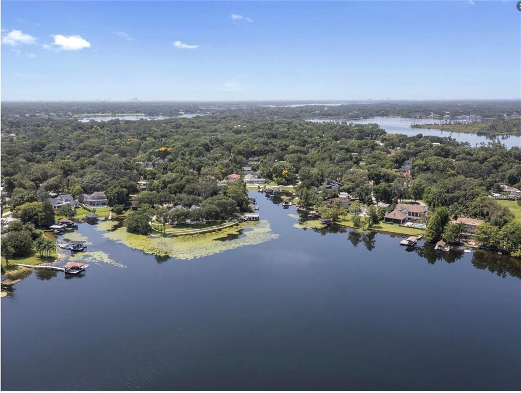 An aerial view of a lakefront residential neighborhood with docks and dense surrounding trees — 212 W 1ST AVENUE, WINDERMERE, FL