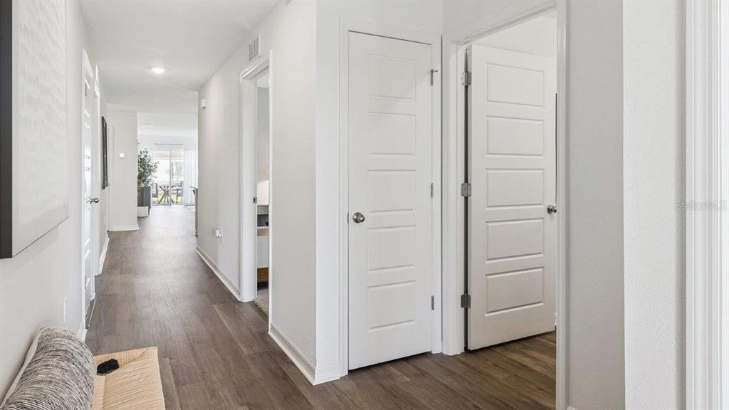A hallway with light wood-look flooring leads to an open living area with white doors — 1126 AMBERS WAVE COURT, LAKE WALES, FL