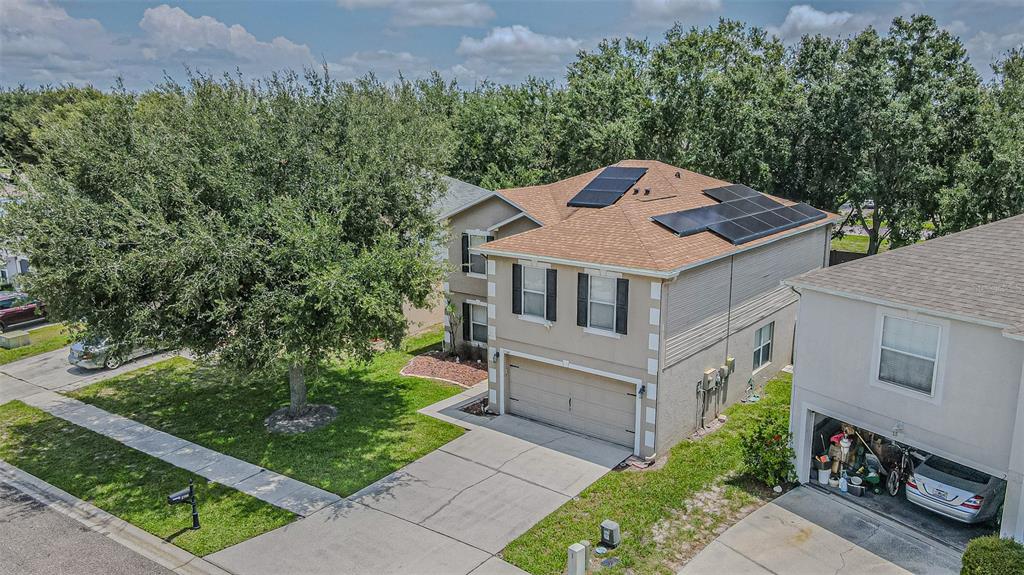 An aerial view of a two-story suburban house with solar panels on the roof — 2706 MINGO DR, LAND O LAKES, FL
