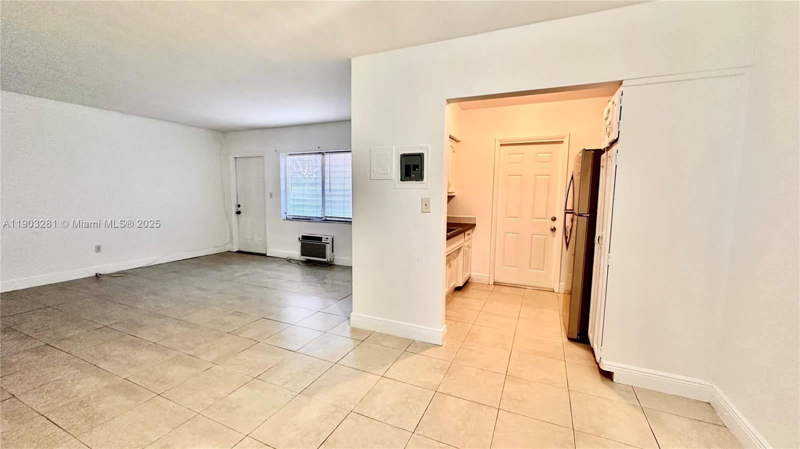 An open-concept living area features light-colored tile flooring, white walls, and an adjacent kitchen — 1955 Normandy Dr # 2, Miami Beach FL 33141, MIAMI BEACH, FL