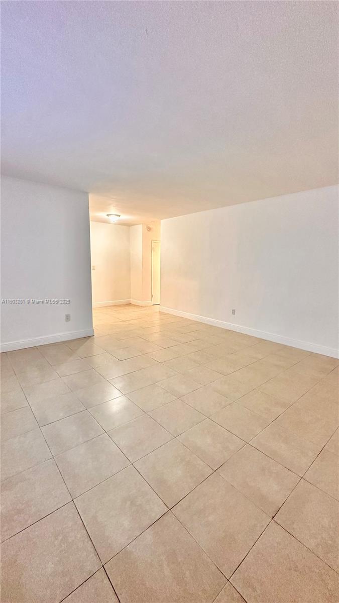 An empty room features white walls and light-colored square floor tiles — 1955 Normandy Dr # 2, Miami Beach FL 33141, MIAMI BEACH, FL