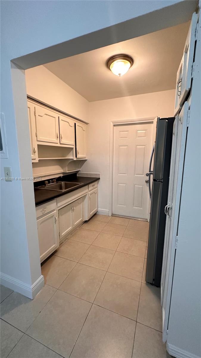 A kitchen features white cabinets, dark countertops, a stainless steel sink, and tile flooring — 1955 Normandy Dr # 2, Miami Beach FL 33141, MIAMI BEACH, FL