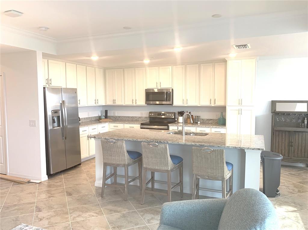 A kitchen features white cabinets, granite countertops, stainless steel appliances, and a central island — 14091 HERITAGE LANDING BOULEVARD UNIT 137, PUNTA GORDA, FL