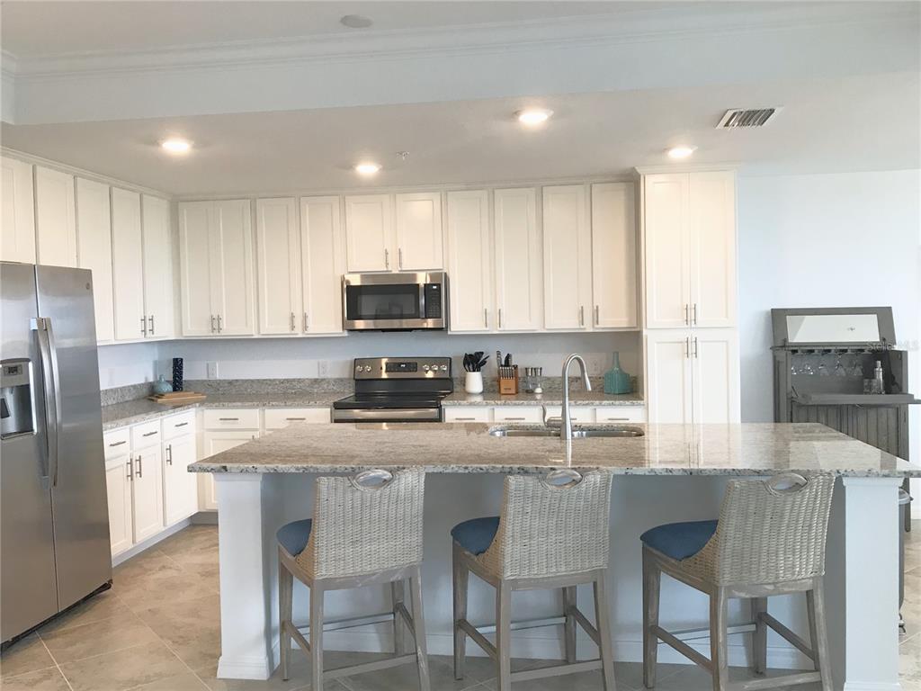 A kitchen features white cabinets, granite countertops, stainless steel appliances, and a central island — 14091 HERITAGE LANDING BOULEVARD UNIT 137, PUNTA GORDA, FL