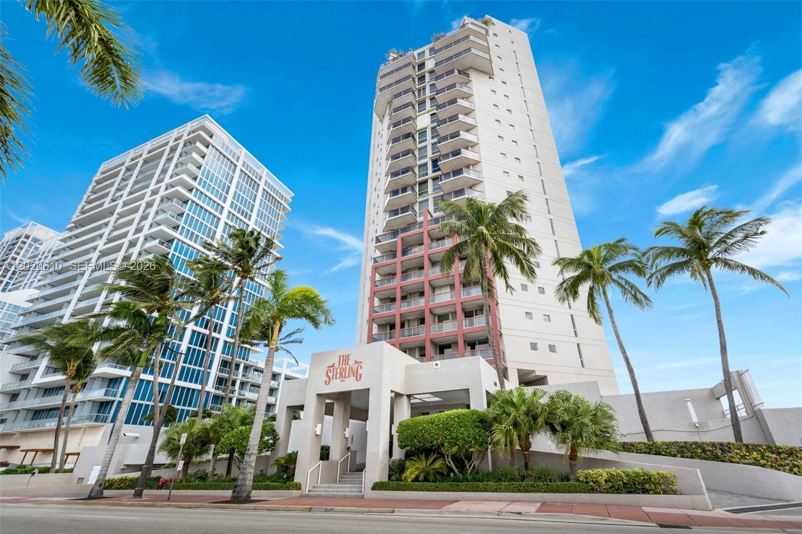 A low-angle exterior view of The Sterling high-rise condominium building with palm trees — MIAMI BEACH, FL