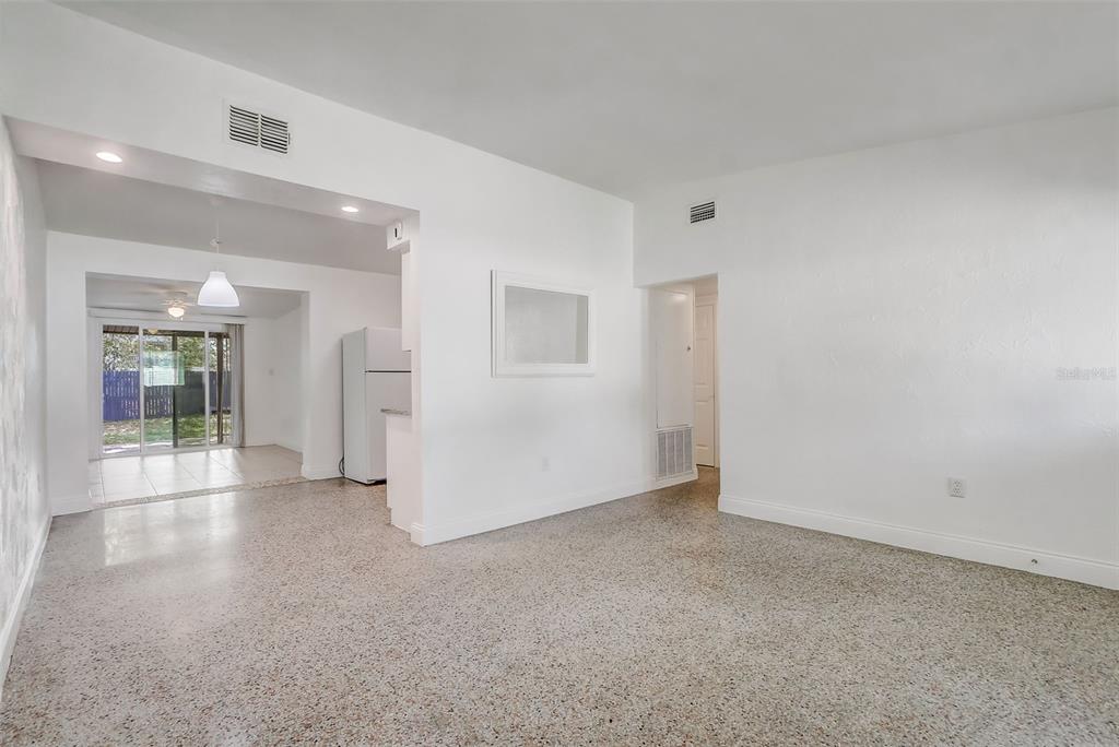 An open-concept living area features white walls, terrazzo flooring, and a view into the kitchen — 6601 HARVEY STREET, ORLANDO, FL