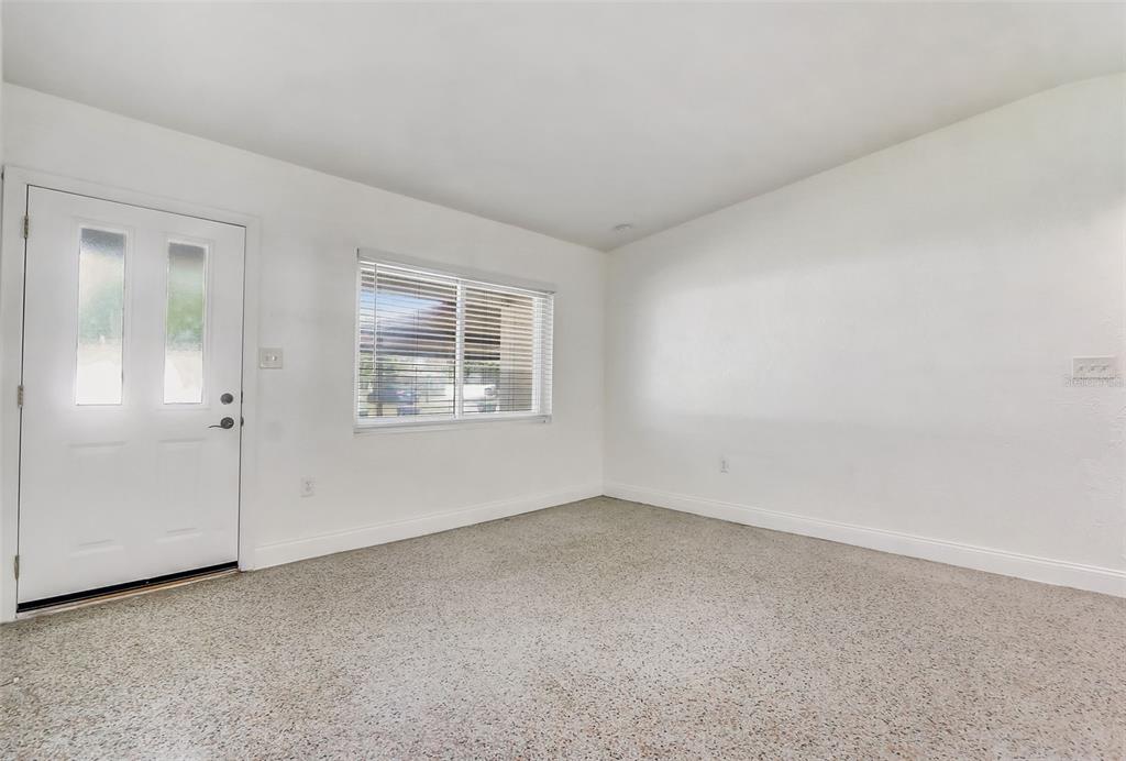An empty room with white walls, beige carpet, a white door, and a window — 6601 HARVEY STREET, ORLANDO, FL