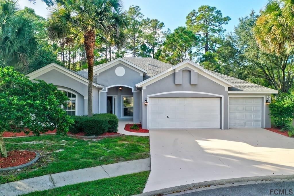 A single-story gray house with a two-car garage and a palm tree in the yard — 7 SHINNECOCK COURT, PALM COAST, FL