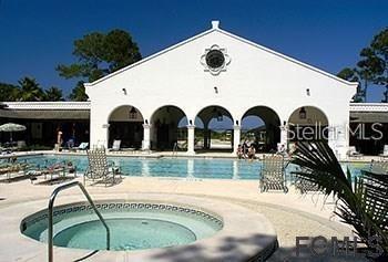 A swimming pool and hot tub are situated in front of a white arched building — 7 SHINNECOCK COURT, PALM COAST, FL
