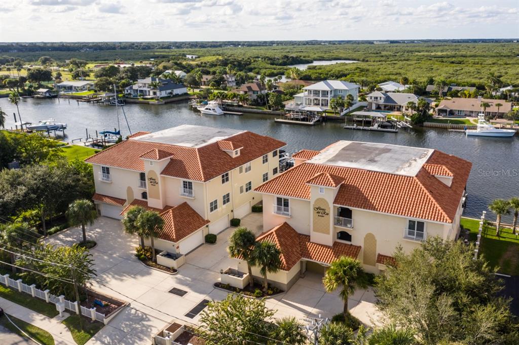 An aerial view shows two multi-story townhomes with orange tile roofs near a canal — 273 MIDDLE WAY UNIT G, NEW SMYRNA BEACH, FL
