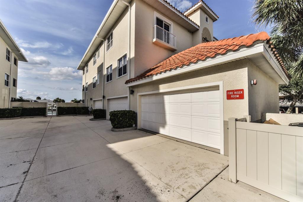 An exterior view of a multi-story building with a garage labeled as a fire riser room — 273 MIDDLE WAY UNIT G, NEW SMYRNA BEACH, FL