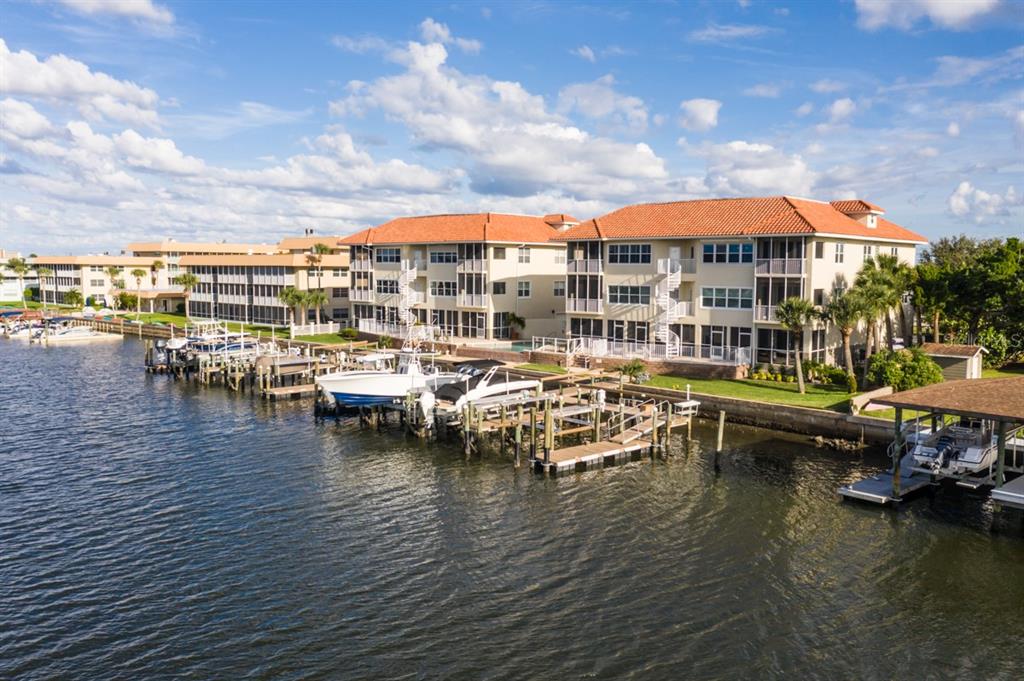 An aerial view shows multi-story waterfront condominiums with boat docks and a blue sky — 273 MIDDLE WAY UNIT G, NEW SMYRNA BEACH, FL
