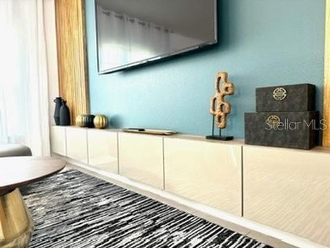 A living room features a wall-mounted television above a long, glossy beige storage console — 50989 HIGHWAY 27 UNIT 333, DAVENPORT, FL