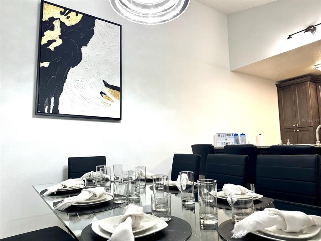 A dining room features a glass table with place settings beneath a large abstract painting — 50989 HIGHWAY 27 UNIT 333, DAVENPORT, FL