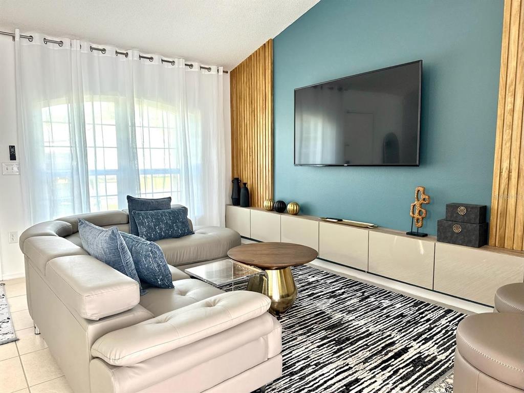A living room features a blue accent wall with wood slats, a television, and sectional seating — 50989 HIGHWAY 27 UNIT 333, DAVENPORT, FL