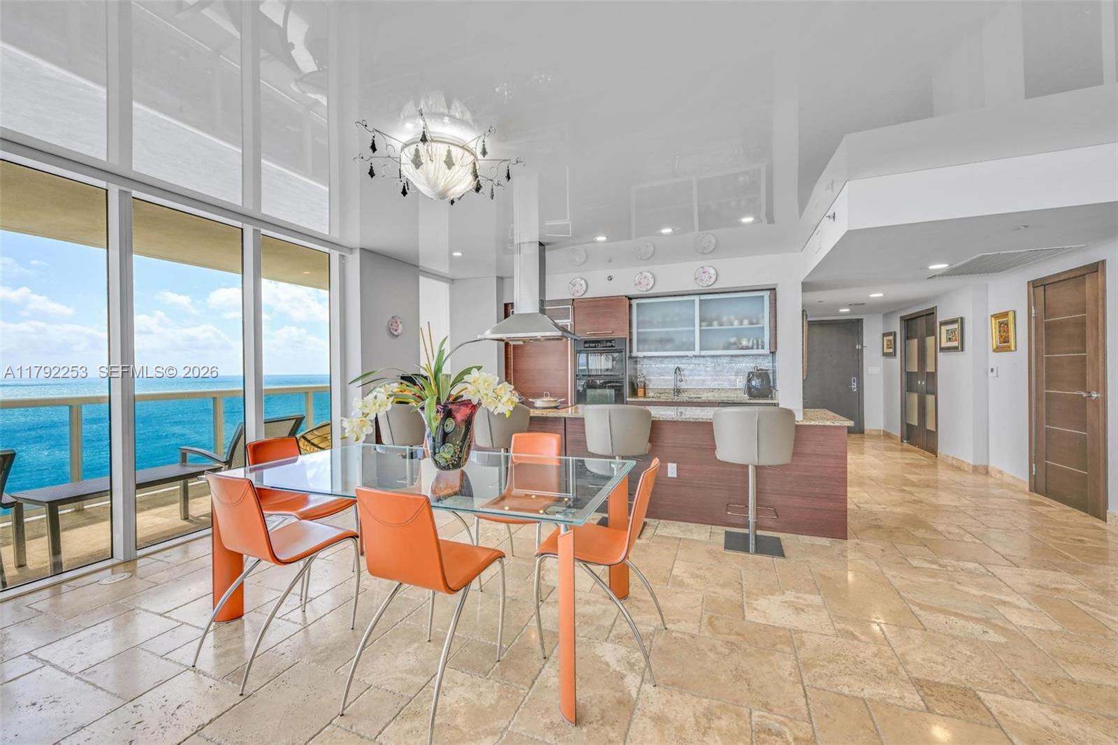 A dining area and kitchen feature orange chairs, a glass table, and ocean views — 1830 S Ocean Dr # 1201, Hallandale Beach FL 33009, HALLANDALE BEACH, FL