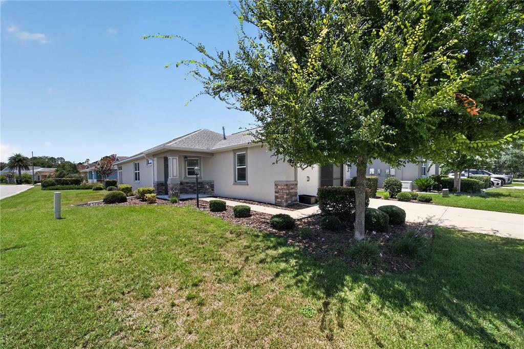 A single-story house with a tan exterior, stone accents, and a large tree in front — 9440 SW 98TH TERRACE, OCALA, FL