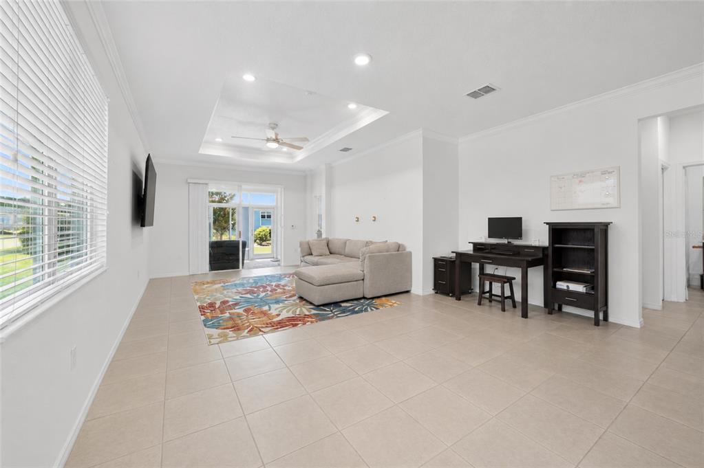 A living room with tile floors, a tray ceiling, a sectional sofa, and a desk — 9440 SW 98TH TERRACE, OCALA, FL