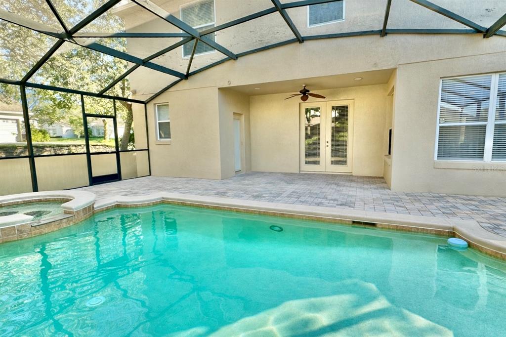 A swimming pool with a spa sits on a patio enclosed by a screen cage — 4410 PINE GOLD AVENUE, APOPKA, FL