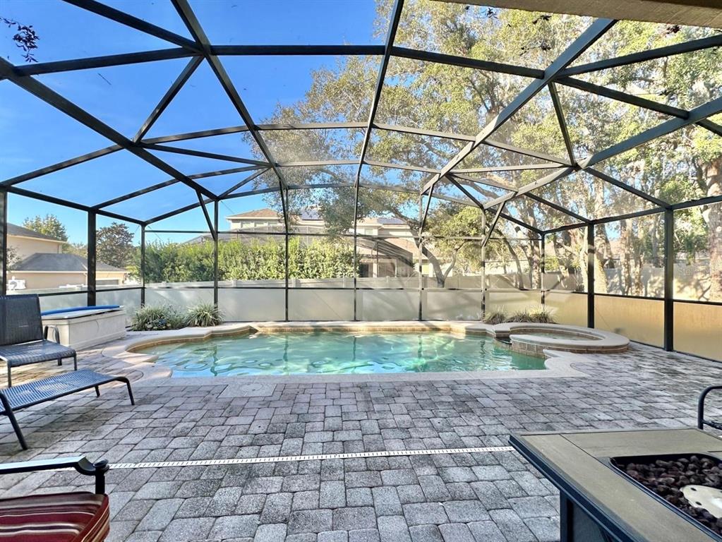 A screened-in patio features a swimming pool, a hot tub, and stone paver flooring — 4410 PINE GOLD AVENUE, APOPKA, FL