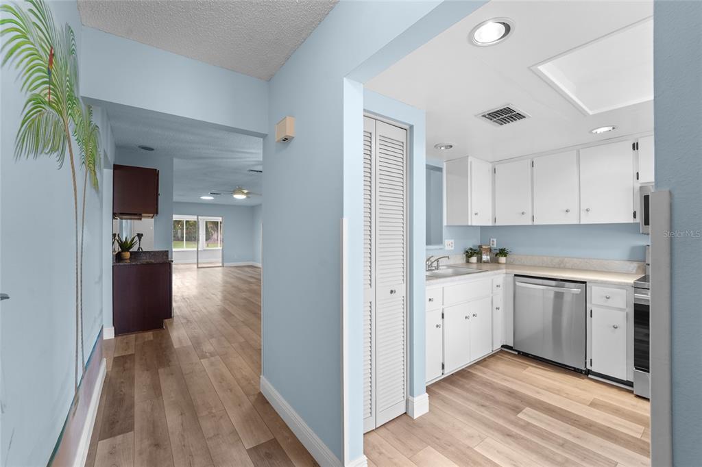 A kitchen features white cabinetry, stainless steel appliances, light countertops, and a window with valance — 3351 STONEHAVEN COURT W UNIT C, PALM HARBOR, FL