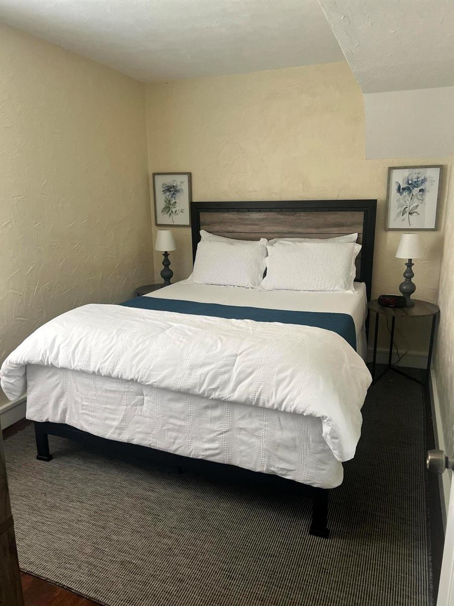 A bedroom features a bed with a dark frame, white bedding, and two bedside lamps — 314 S L Street, FL 33460, FL