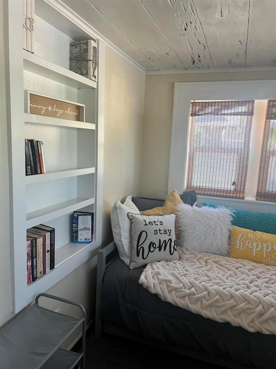 A cozy bedroom features a built-in white bookshelf, a daybed with decorative pillows, and windows — 314 S L Street, FL 33460, FL