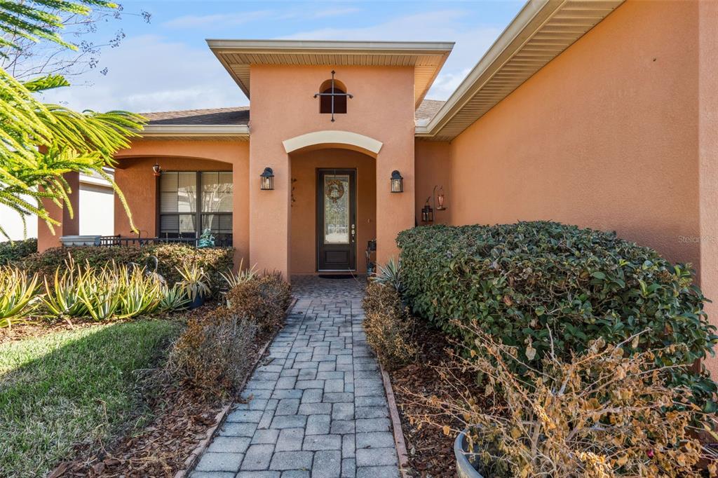 A paved walkway leads to the front entrance of a peach-colored stucco house — 116 GLENDALE COURT, KISSIMMEE, FL