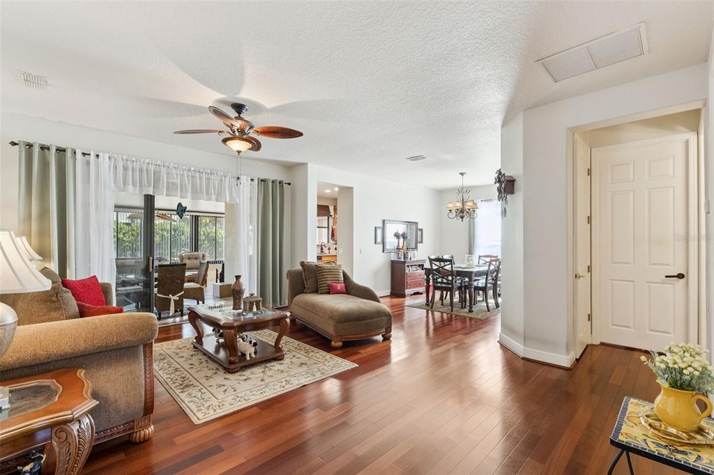A living room and dining area with hardwood floors, a ceiling fan, and sliding doors — 116 GLENDALE COURT, KISSIMMEE, FL