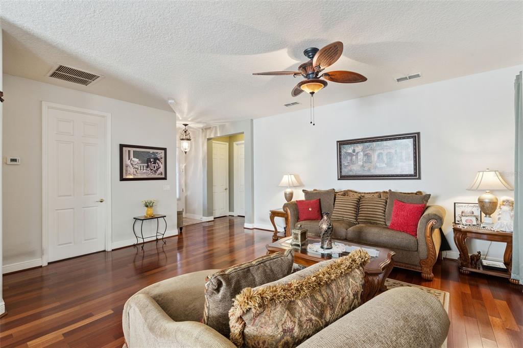 A living room features hardwood floors, a ceiling fan, and a brown sofa — 116 GLENDALE COURT, KISSIMMEE, FL