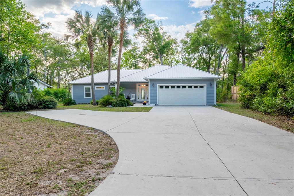 A single-story house with blue siding, a white metal roof, and a concrete driveway — 3709 NW 67TH TERRACE, BELL, FL