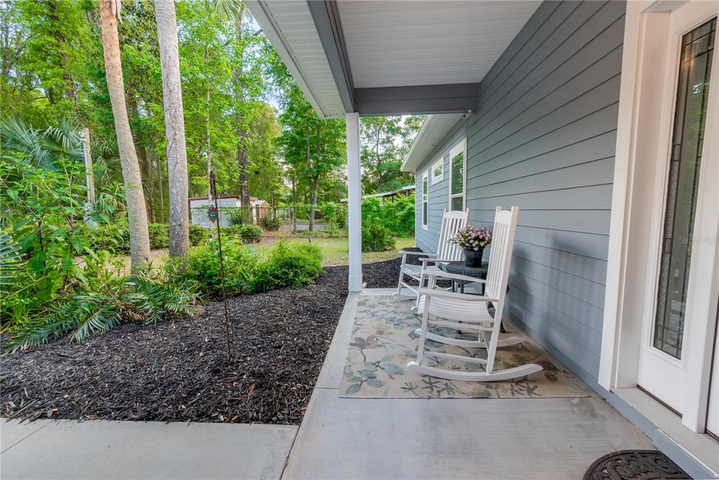 A covered front porch features two white rocking chairs on a patterned rug — 3709 NW 67TH TERRACE, BELL, FL