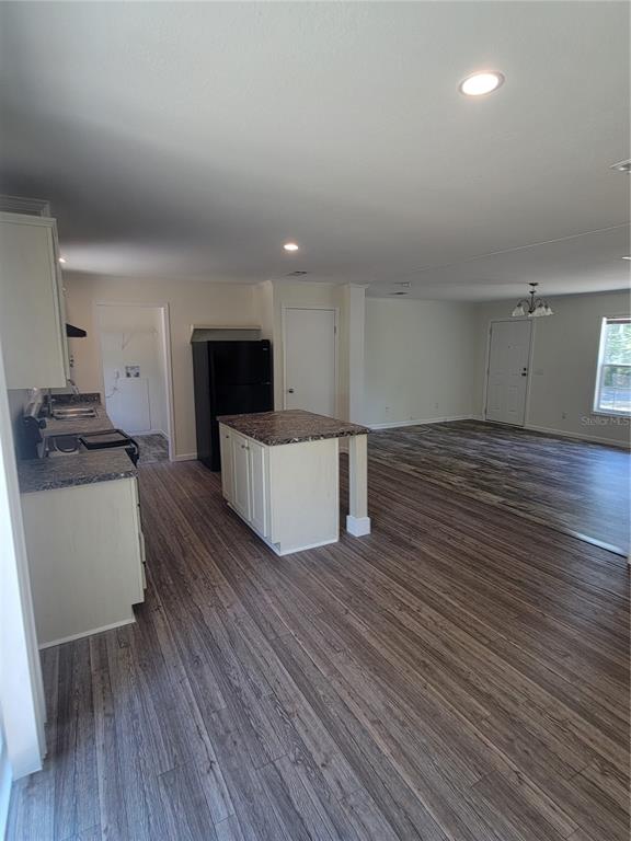 An open-concept kitchen and living area feature wood-look flooring, white cabinets, and a kitchen island — 2435 MYER AVENUE, LEESBURG, FL