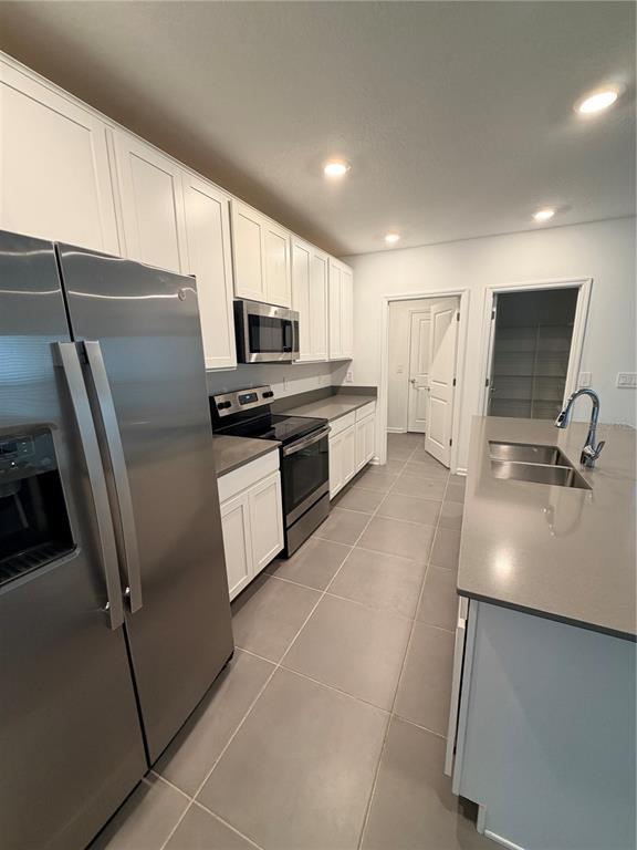 A modern kitchen features white cabinets, stainless steel appliances, and a large gray island — 926 JACKSON AVENUE, DAVENPORT, FL