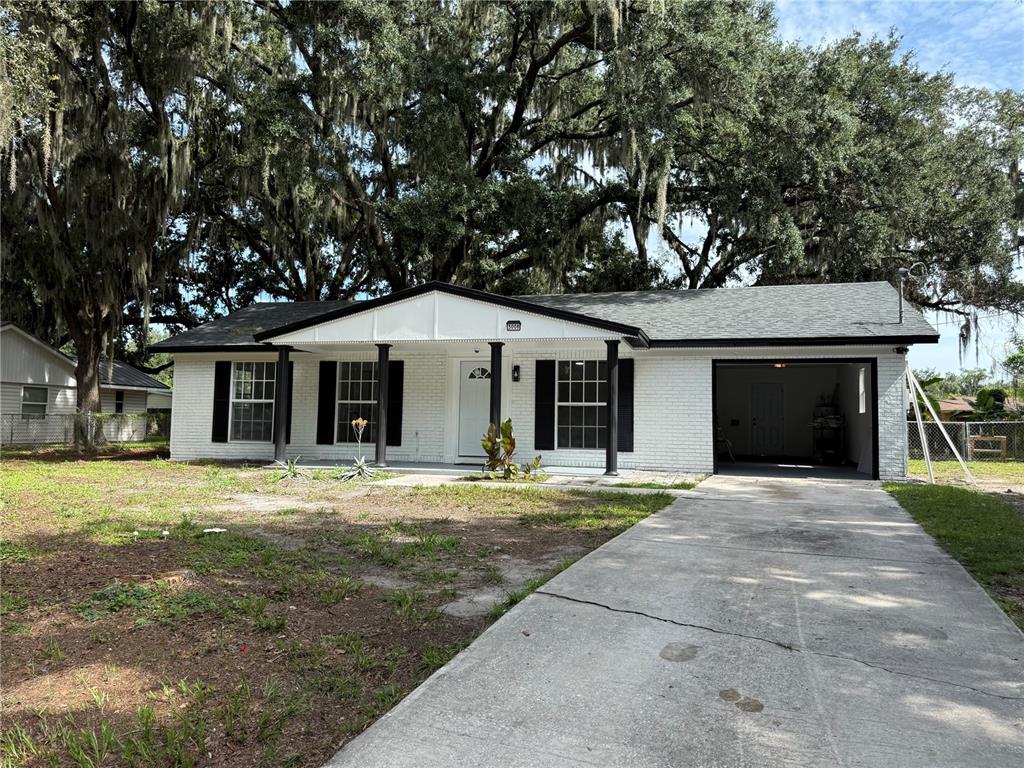 A single-story white brick house with black shutters and a front porch under large trees — 3008 OAKVIEW LANE, PLANT CITY, FL