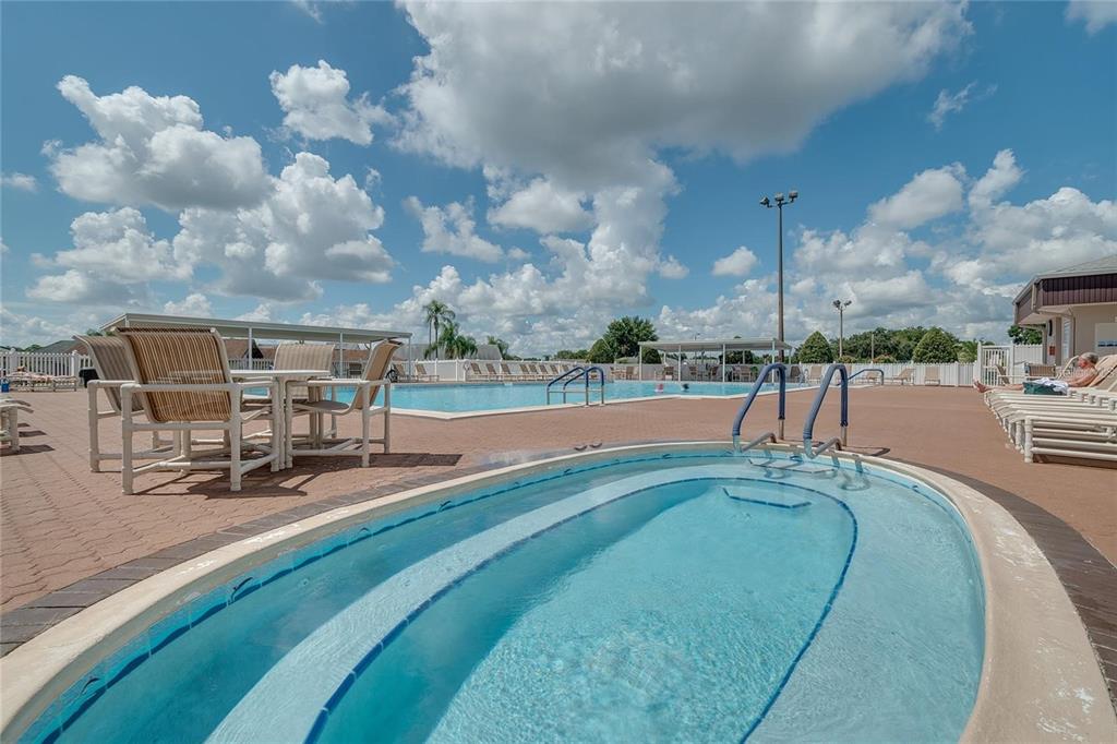 A swimming pool and a hot tub are located on a paved patio under blue skies — 5987 TEAL TRAIL, LAKELAND, FL