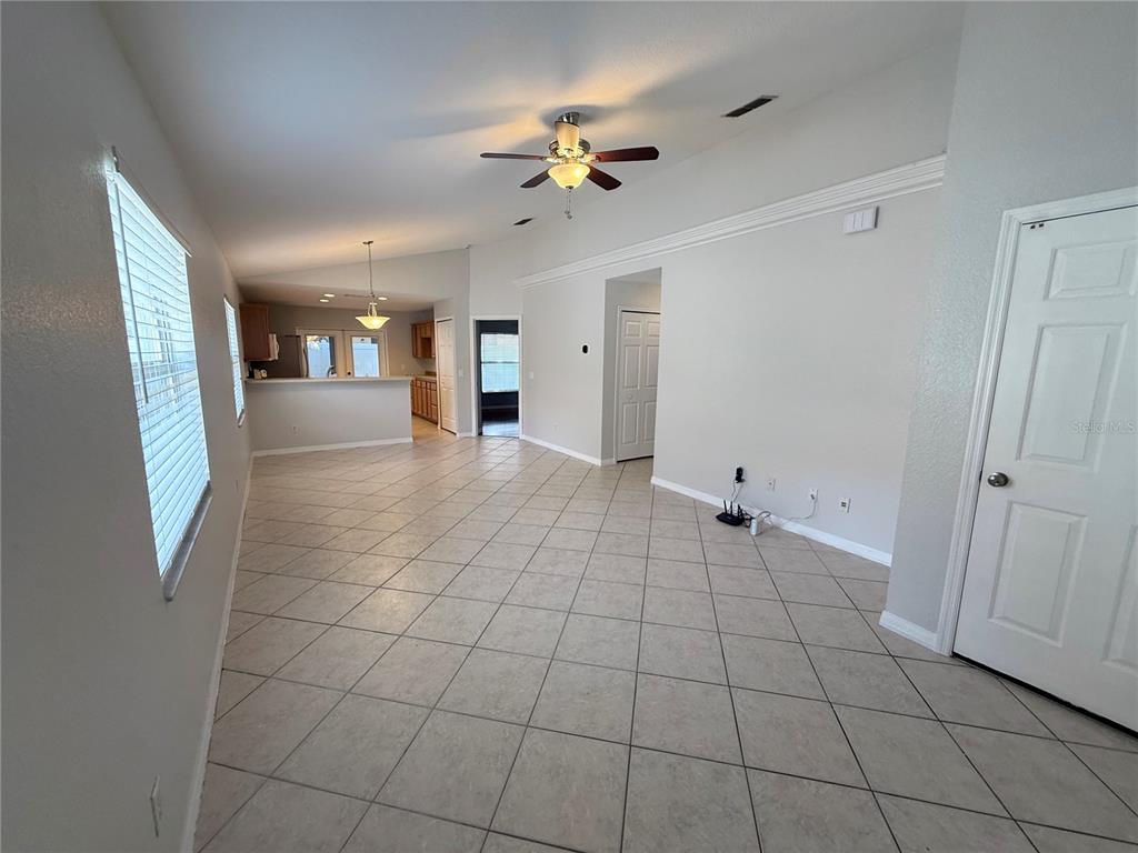 An open-concept living area features light-colored tile flooring, vaulted ceilings, and a kitchen pass-through — 1084 AMANDA KAY CIRCLE, SANFORD, FL
