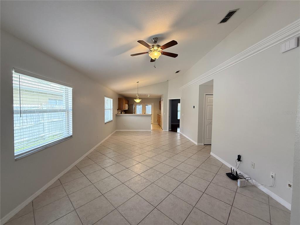 An open-concept living area features light-colored tile flooring, a ceiling fan, and a kitchen pass-through — 1084 AMANDA KAY CIRCLE, SANFORD, FL