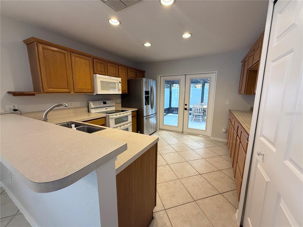 A kitchen with oak cabinets, laminate countertops, stainless steel appliances, and tile flooring — 1084 AMANDA KAY CIRCLE, SANFORD, FL