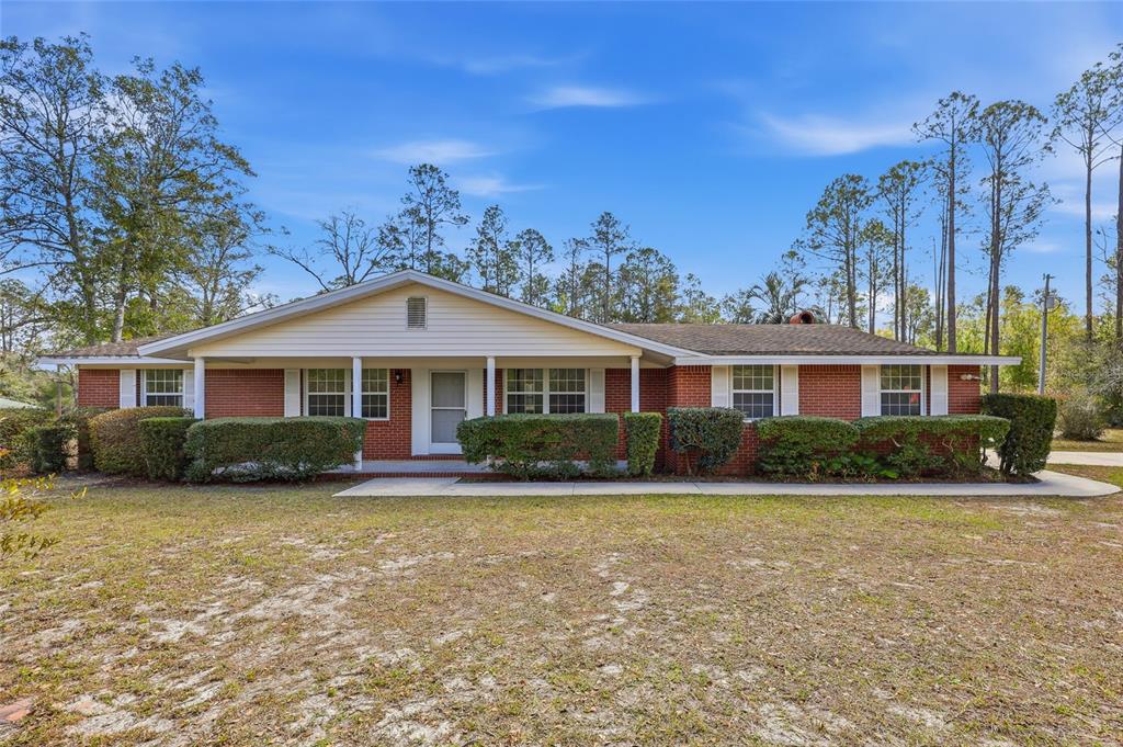 A single-story brick house with a covered front porch and a large grassy yard — 129 SW BENZ WAY, LAKE CITY, FL