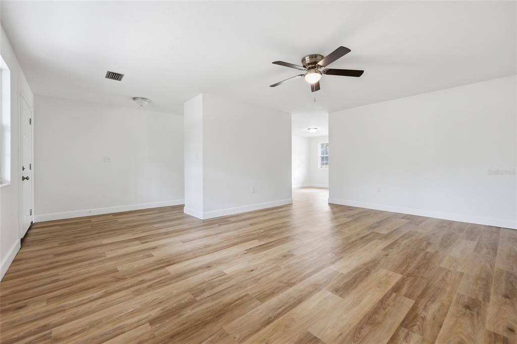 An empty room with light wood-look flooring, white walls, and a ceiling fan — 129 SW BENZ WAY, LAKE CITY, FL