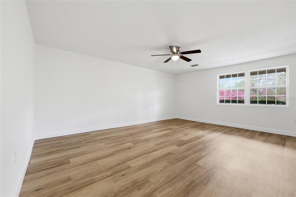 An empty room features white walls, light wood-look flooring, and a ceiling fan — 129 SW BENZ WAY, LAKE CITY, FL