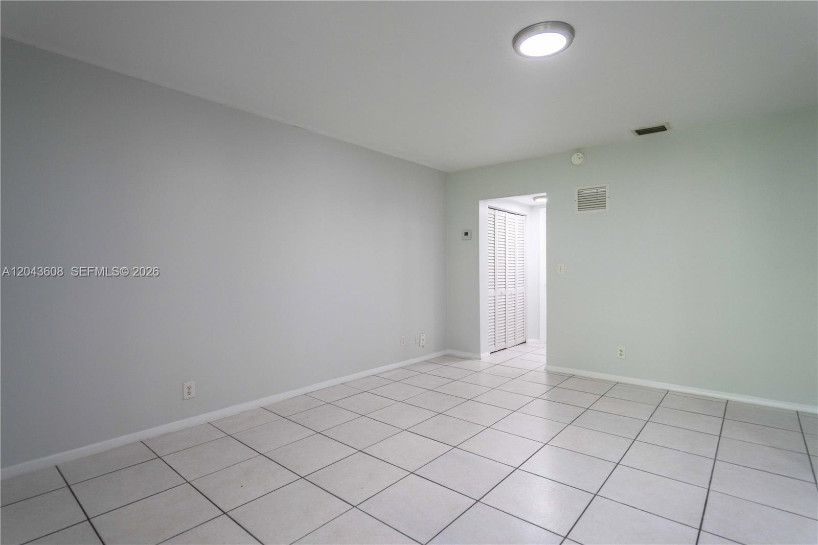 An empty room features light gray walls, white tile flooring, and a doorway with louvered closet doors — 666 NE 80th St # 8, Miami FL 33138, MIAMI, FL